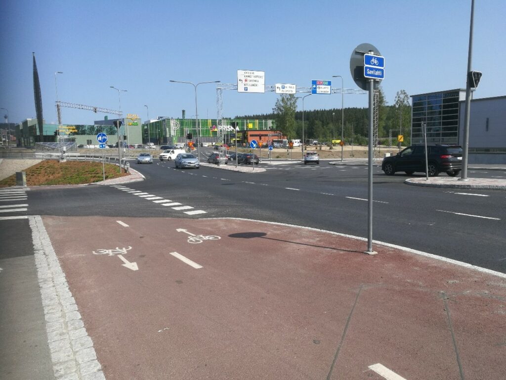 Kuvassa liikenneväyliä ja liikennemerkkejä autoilijoilla ja pyöräilijöille. Urbaani näkymä katualueelta.