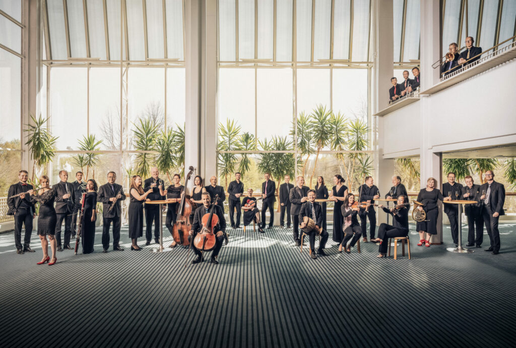 Kuopion kaupunginorkesterin imagokuva, soittajat musiikkikeskuksen valoaulassa