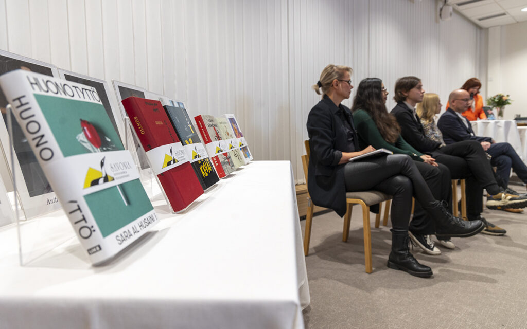 Kuvassa etualalla Savonia-kirjallisuuspalkintoehdokaskirjat ja taustalla kirjailijat