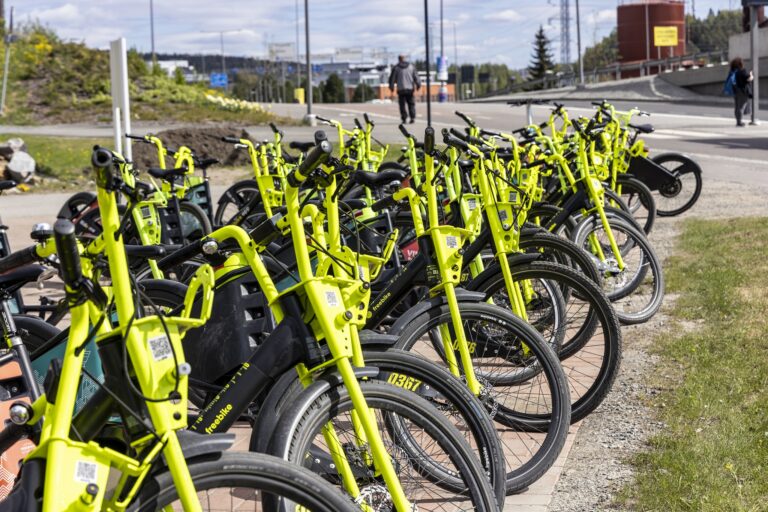 Kaupunkipyöriä rivissä keväisellä kadulla.