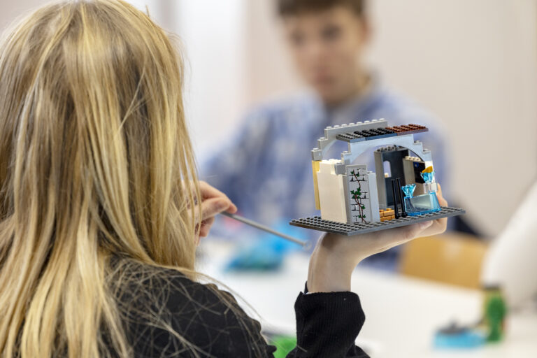 Kaksi nuorta keskustelevat ja rakentavat legoja.