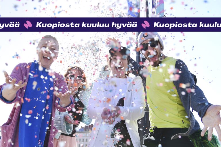 Kuva, josta kolme iloista ihmistä heittää konfettia. Päällä teksti: Kuoiposta kuuluuu hyvää.